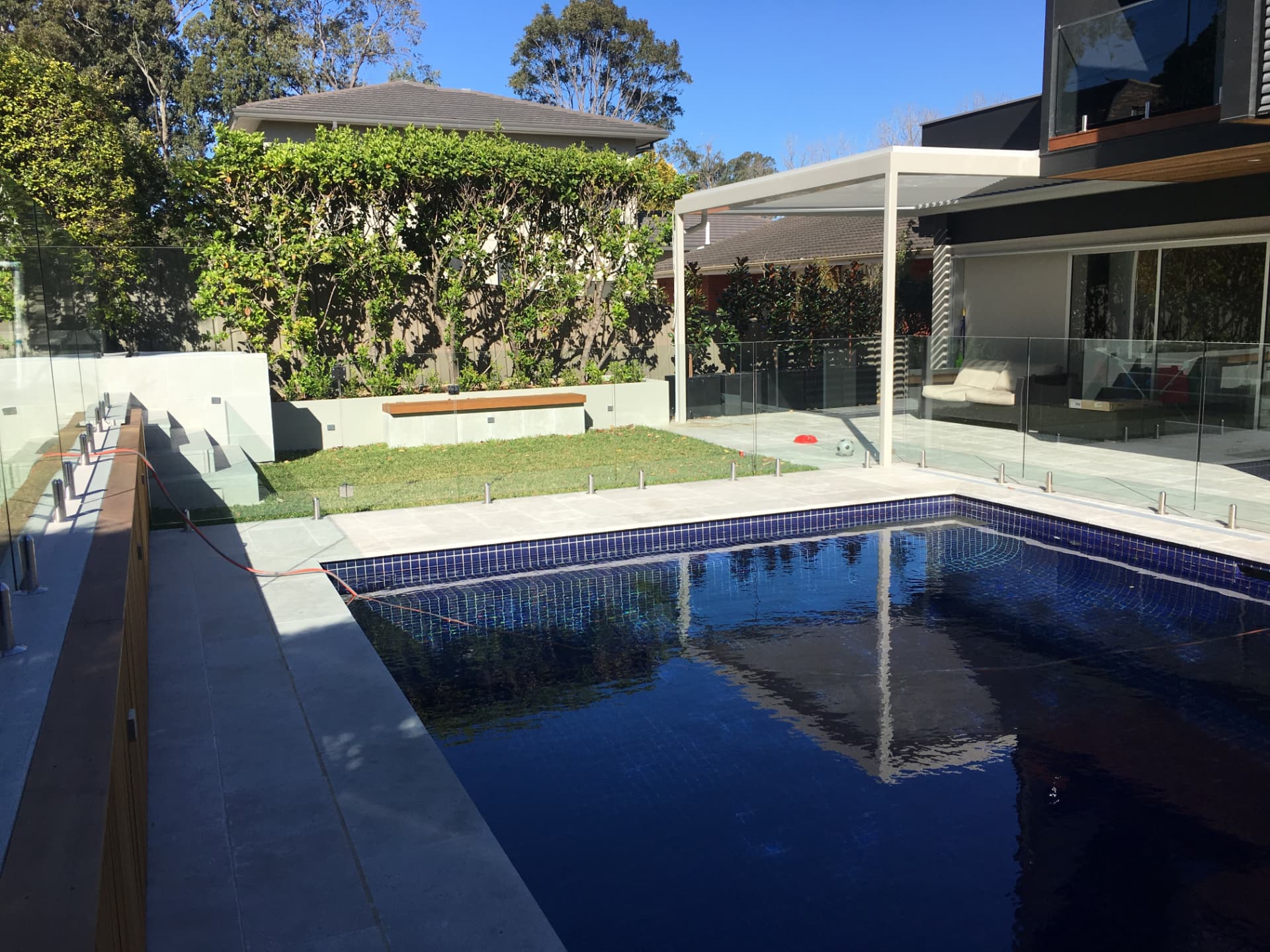 Riverview pool beside the louvred pergola terrace, glass fencing and tiered garden beds