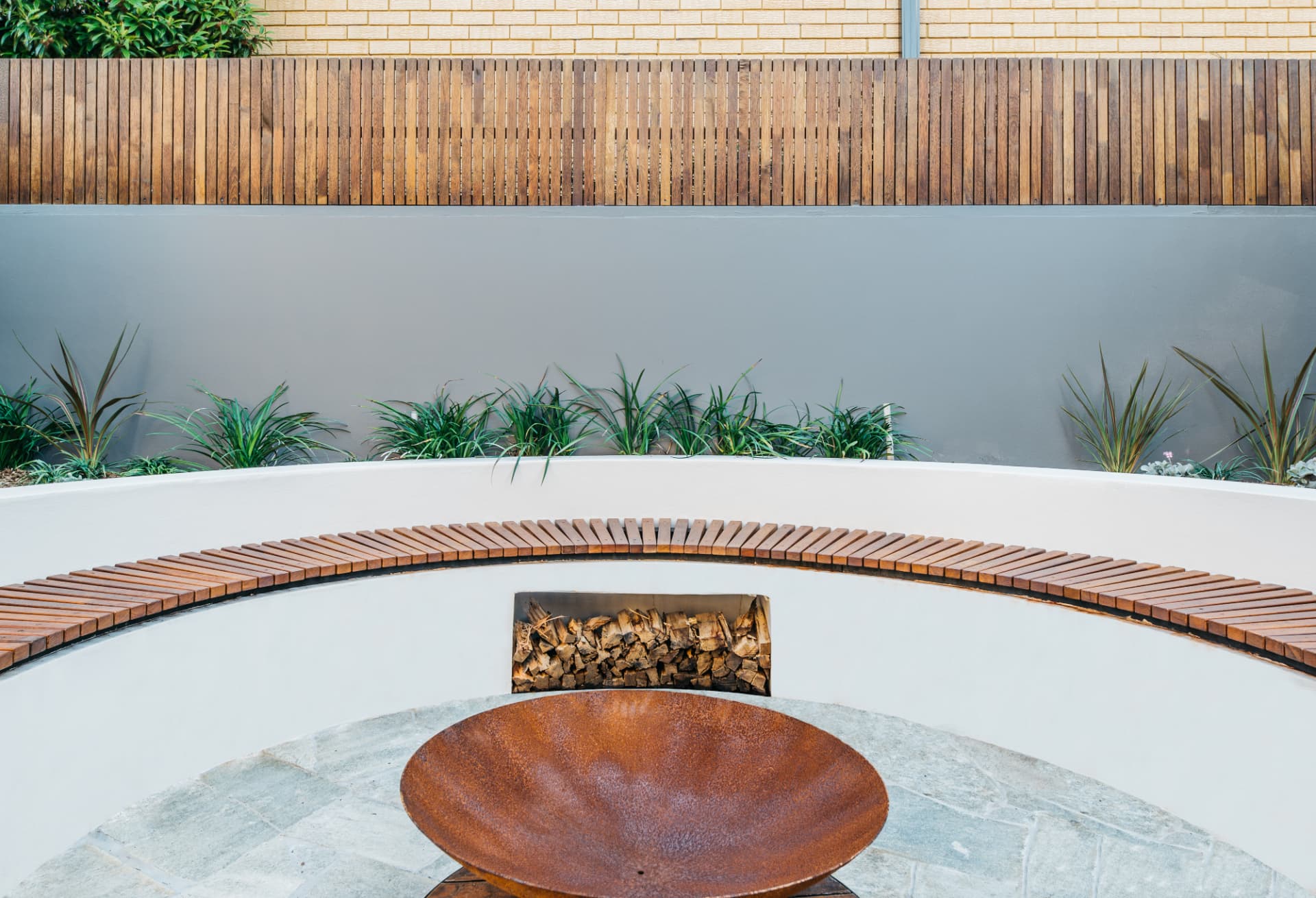 Curved timber bench seating with firewood storage above the Wareemba fire pit