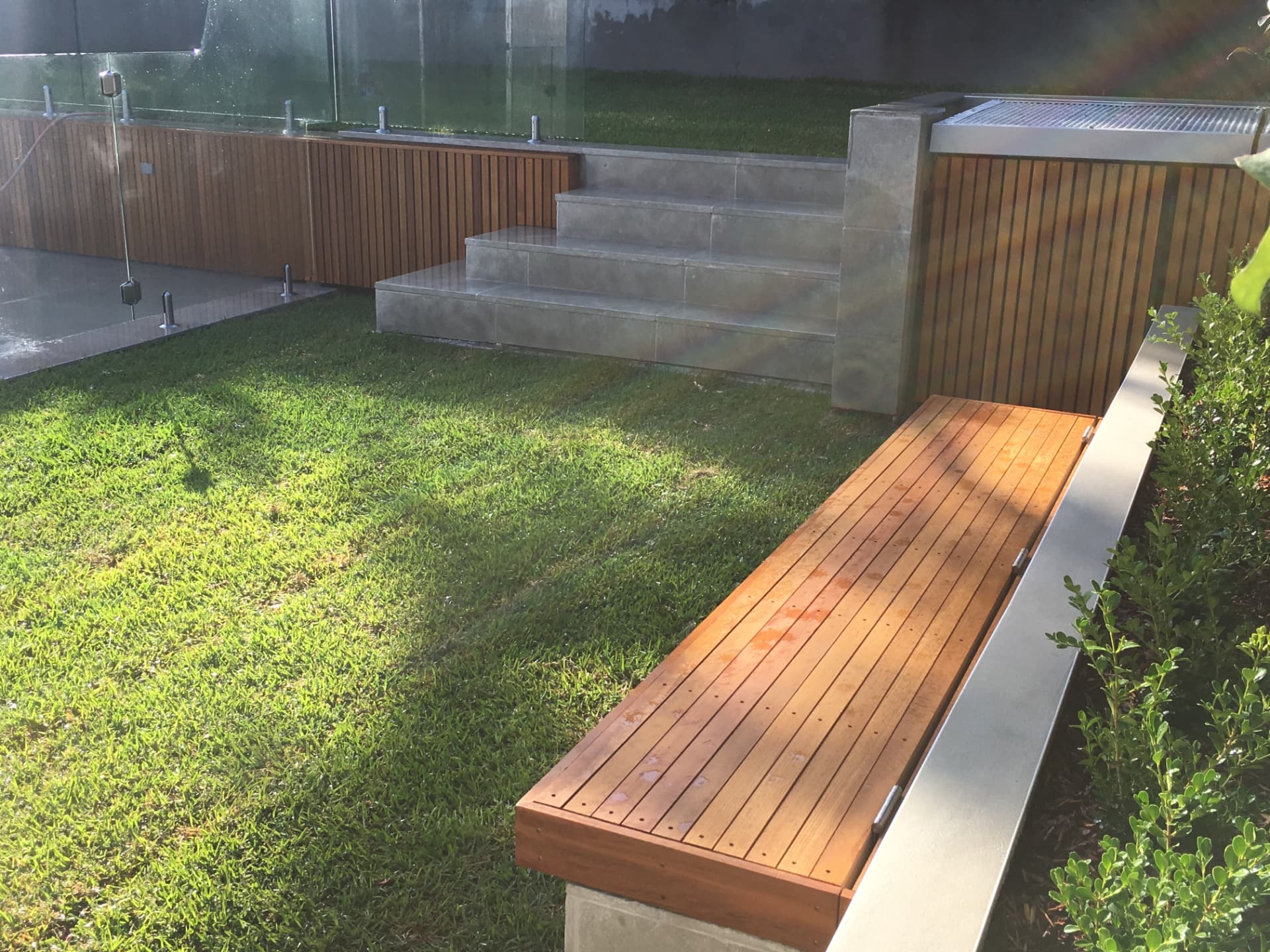 Timber bench seat and pool box beside glass fencing at the Riverview lawn terrace