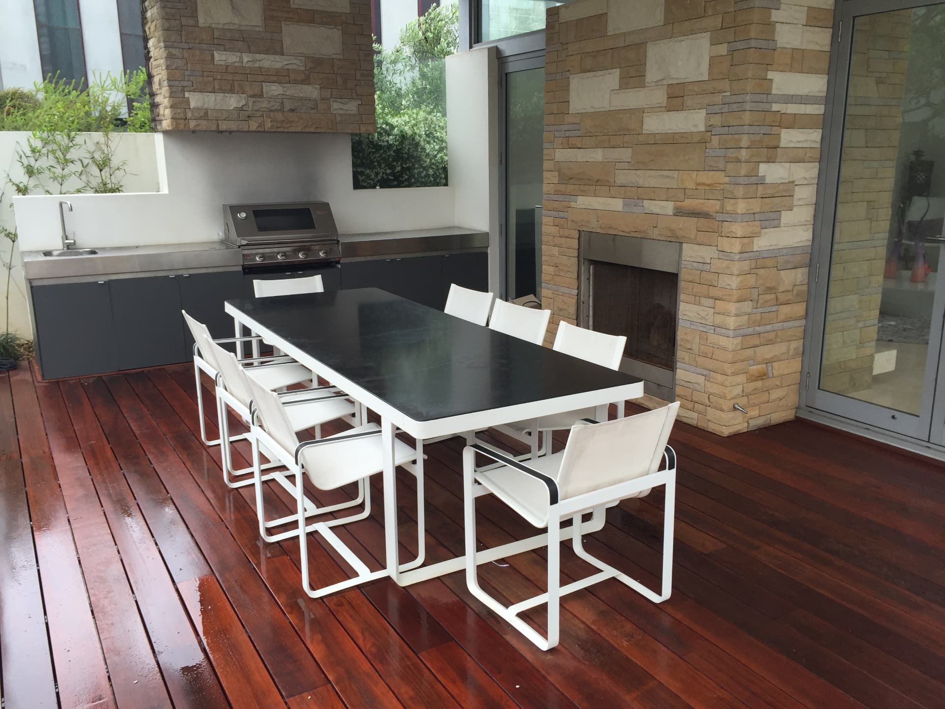 Pavilion outdoor kitchen and dining area with stone fireplace on the timber deck