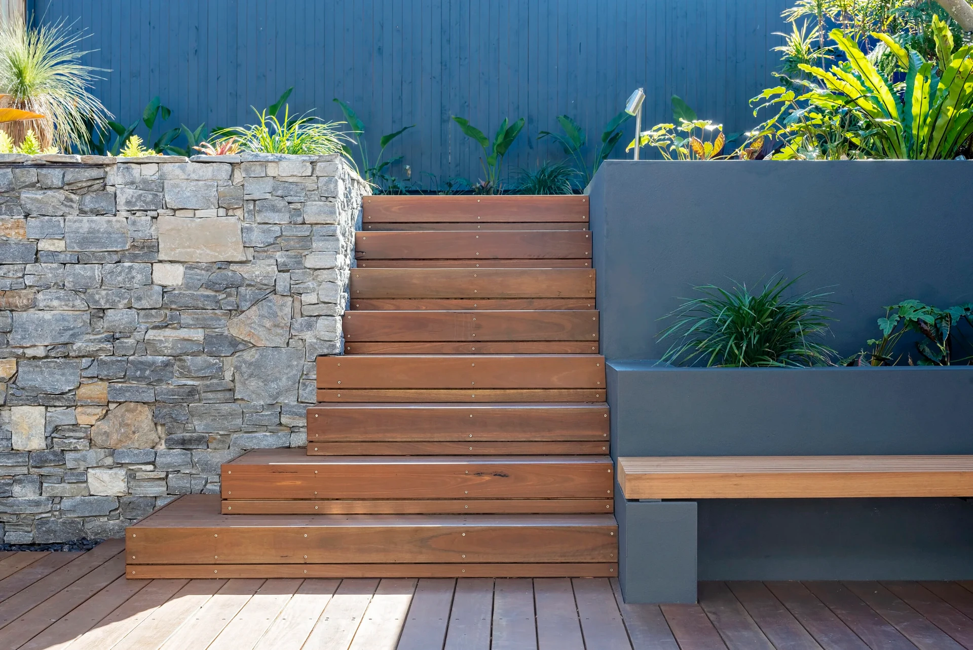 Feature hardwood stairs between the stone-clad water wall and rendered garden planter in Greenwich