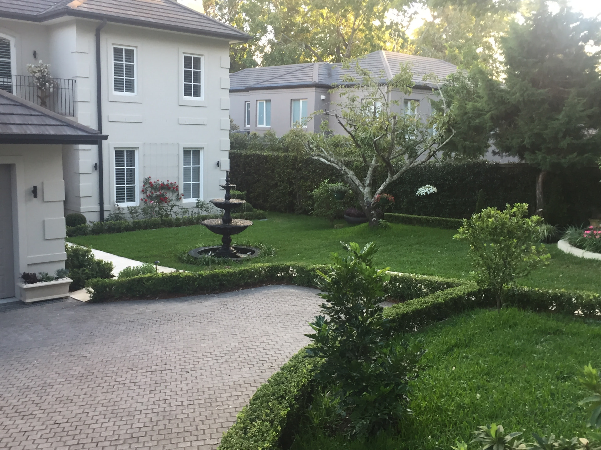 The Warrawee front garden with three-tier fountain, clipped hedges, lawn and cobblestone driveway