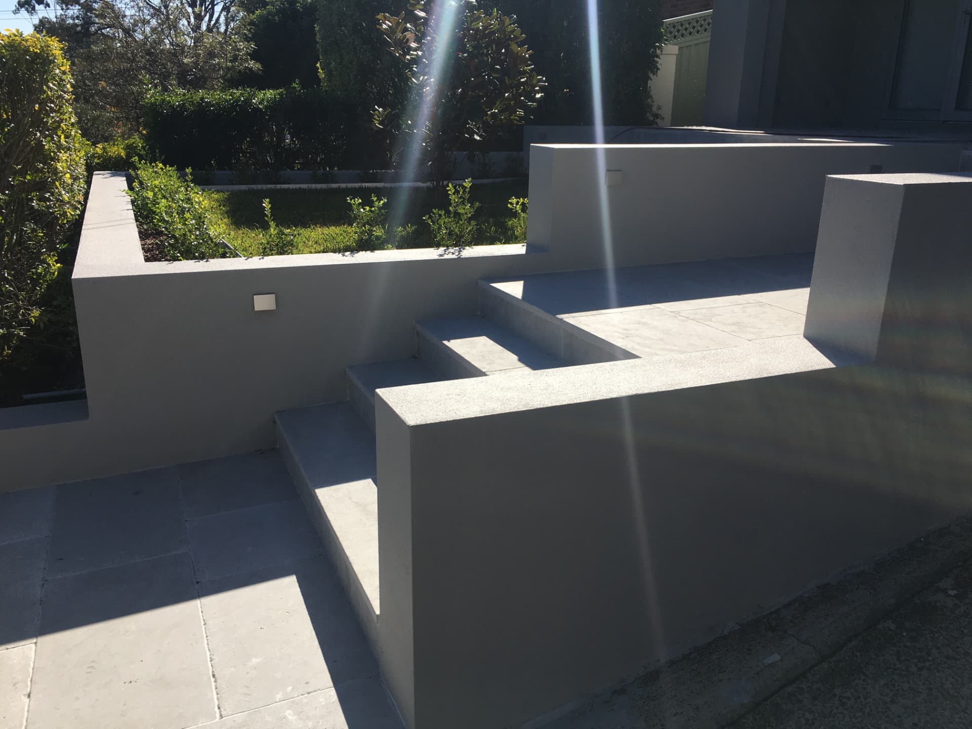 Tiered rendered planter walls and paved steps beside the Riverview garden