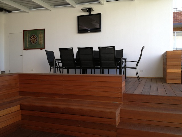 Covered outdoor dining area with hardwood bench seating at the Kingsford home