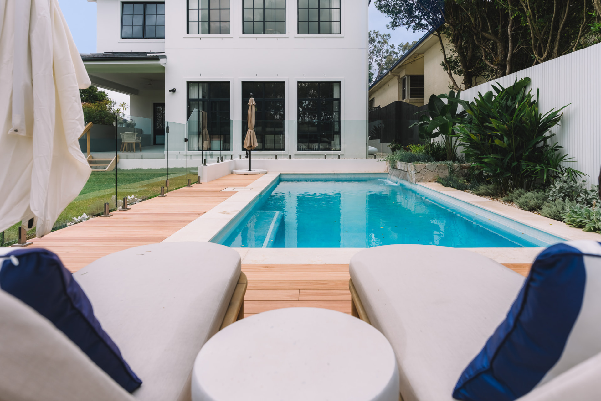 Completed Chatswood pool beside the hardwood deck with sun loungers and frameless glass fencing