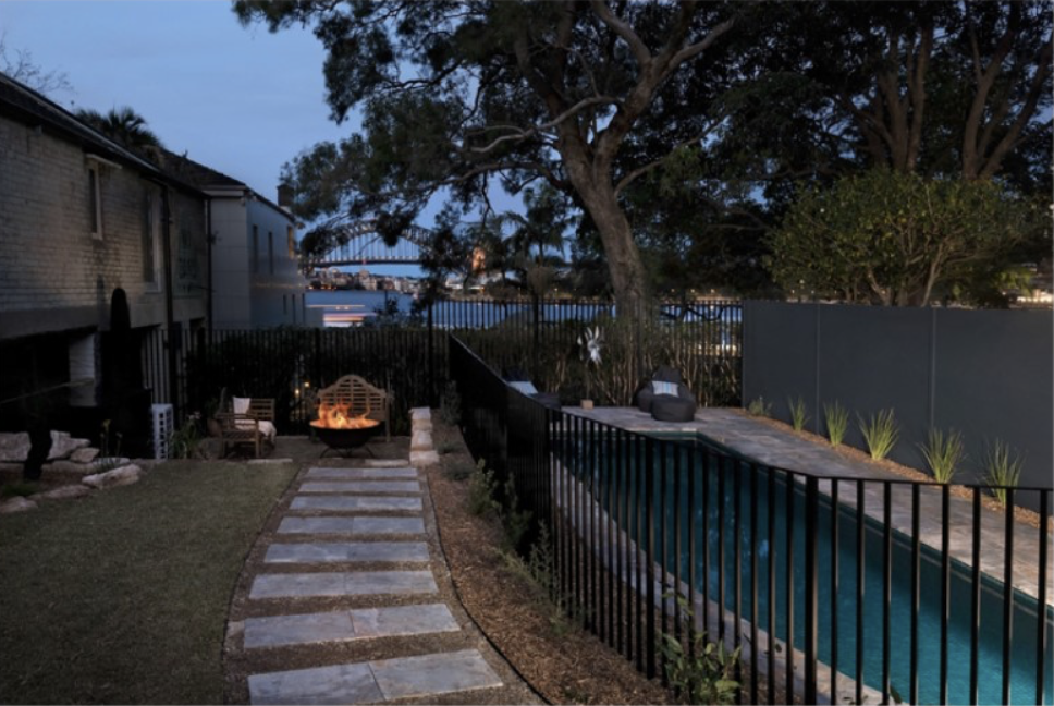 Fire pit area, lawn and step stone path beside the pool at dusk