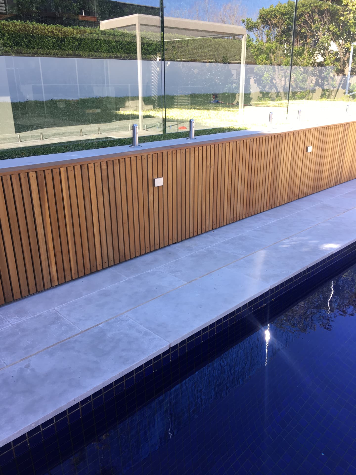 Riverview pool with silver-grey stone coping, deep blue tiled water and timber battened fence