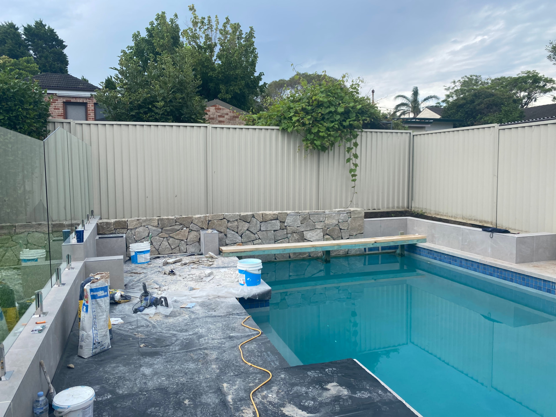 During construction - North Ryde pool renovation with stone wall and timber bench framing underway
