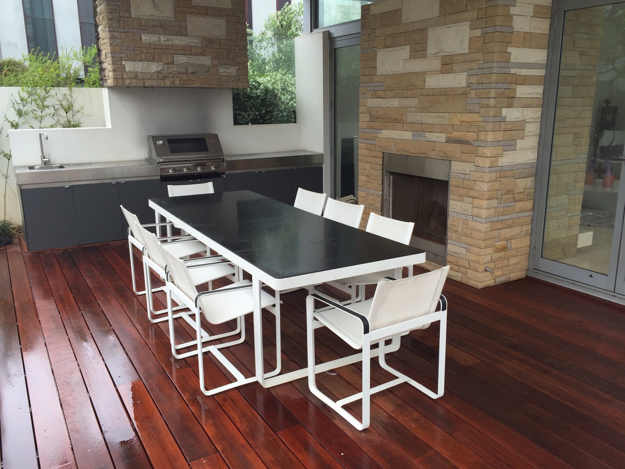 Outdoor dining area with hardwood deck, built-in kitchen and stone-clad fireplace