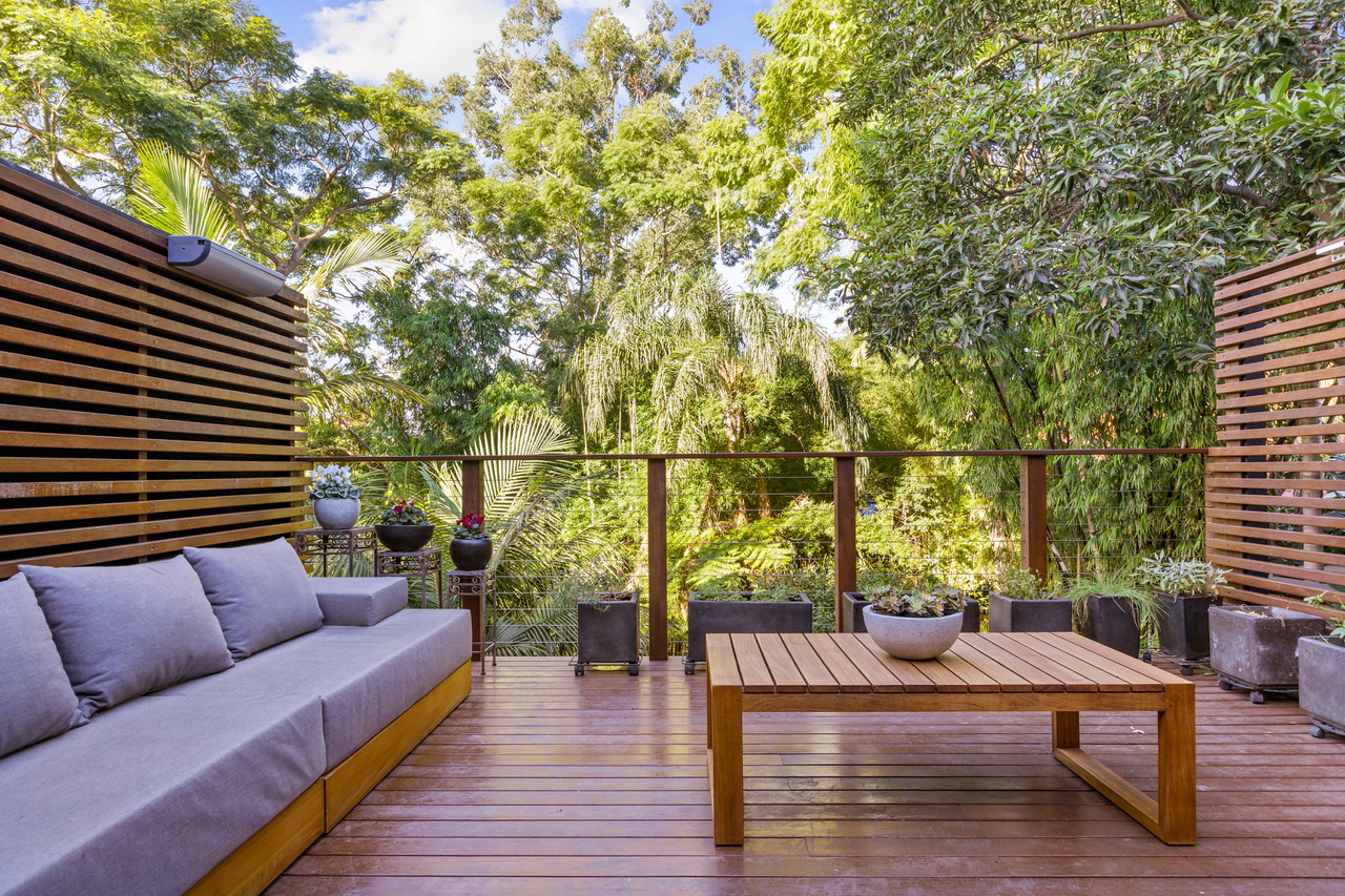 Timber entertaining deck with built-in lounge seating, privacy screens and garden views in Kirribilli