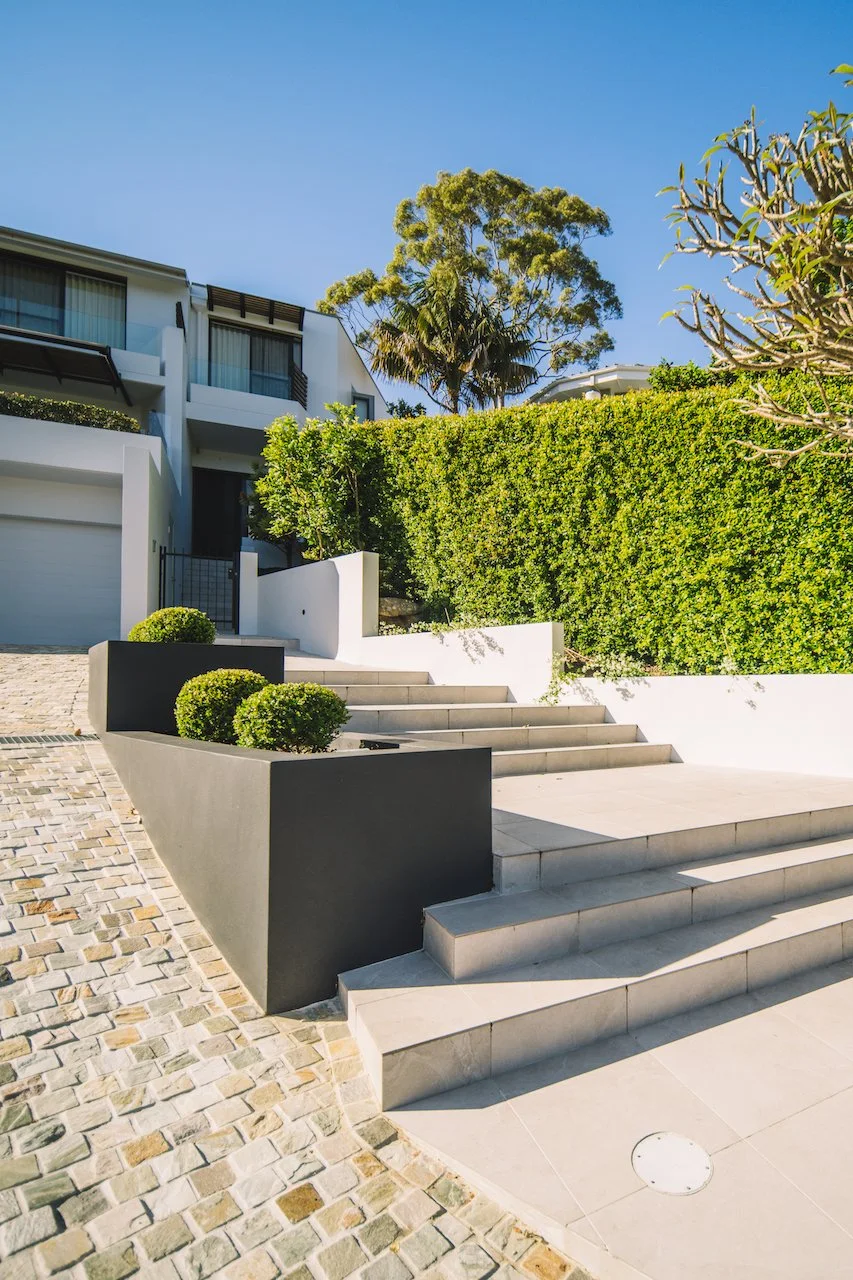 Northbridge tiled entrance stairs beside dark garden planters and cobblestone paving