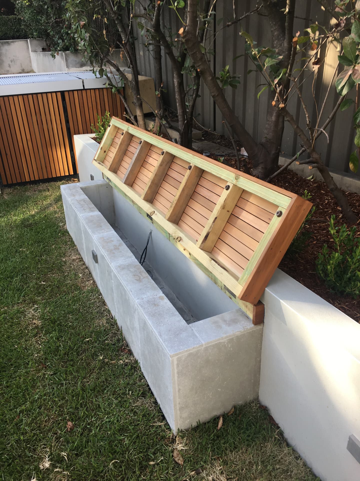 Bench seat with open storage lid revealing the pool box, beside the timber gate at Riverview