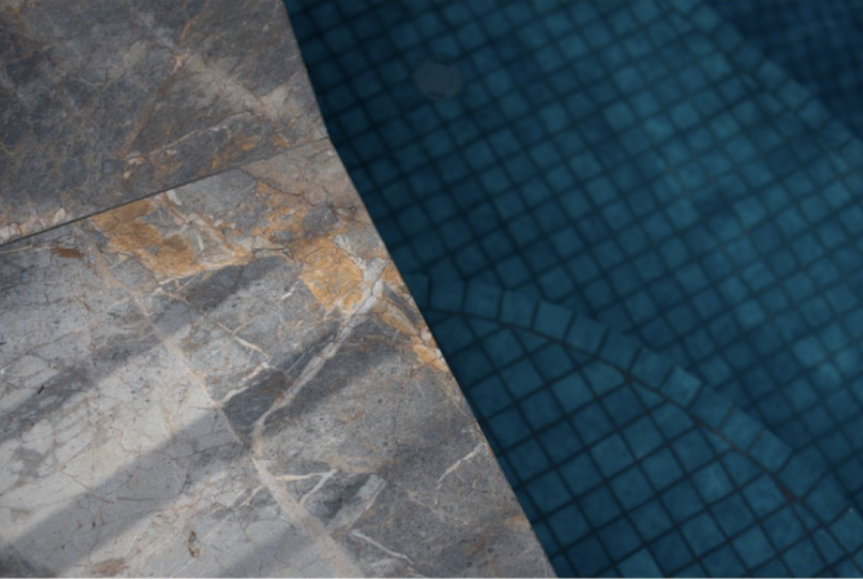 Marble pool coping detail beside the blue mosaic tiled pool