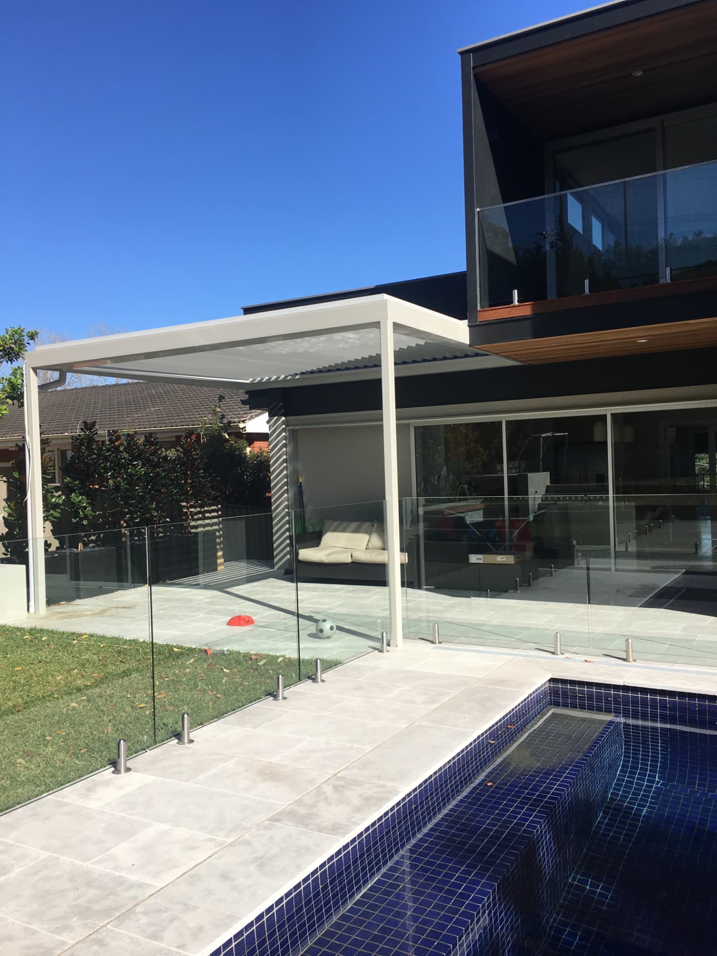 Louvred pergola over the Riverview entertaining terrace with frameless glass fencing and pool beyond