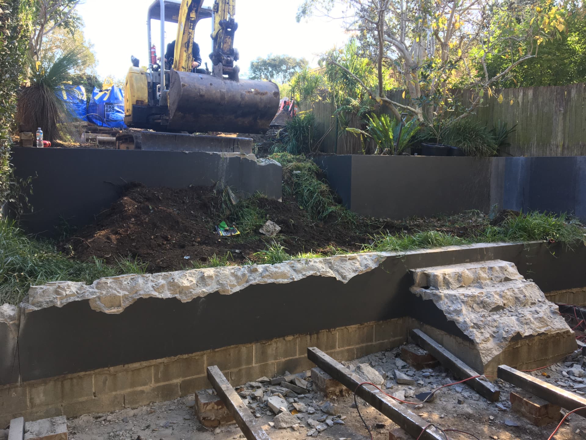 Before - excavator demolishing the old retaining and rendered walls during the Greenwich backyard renovation
