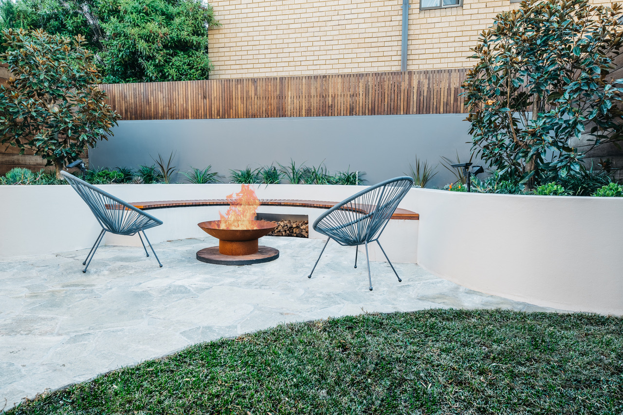 Curved garden courtyard with built-in timber bench seating and a central fire pit