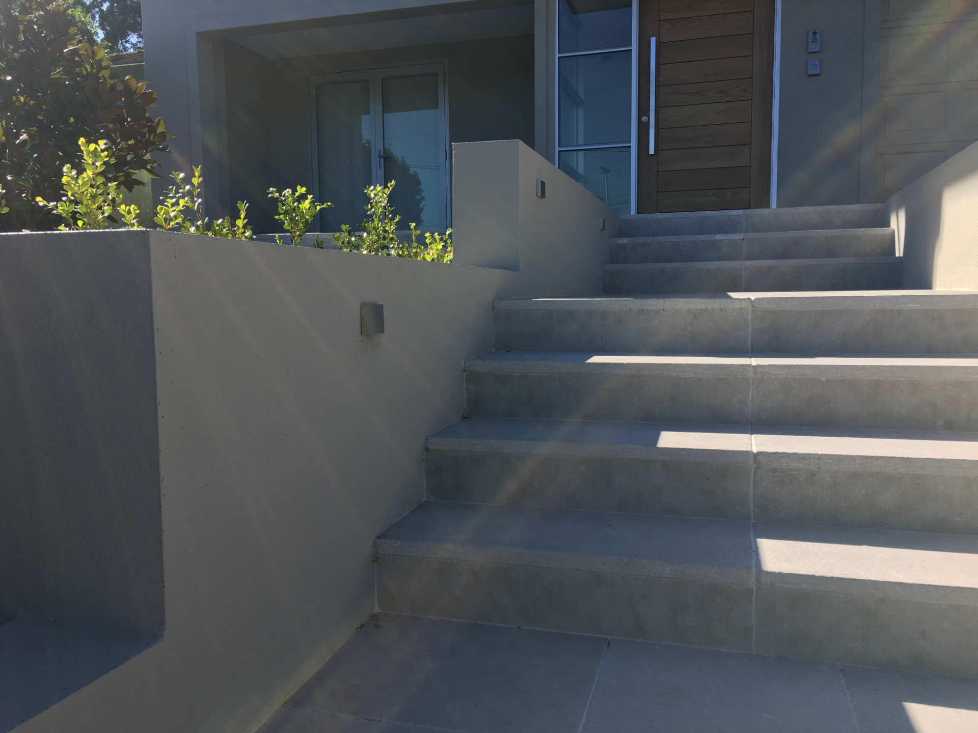 Tiled entrance stairs climbing between rendered planter walls at the Riverview home