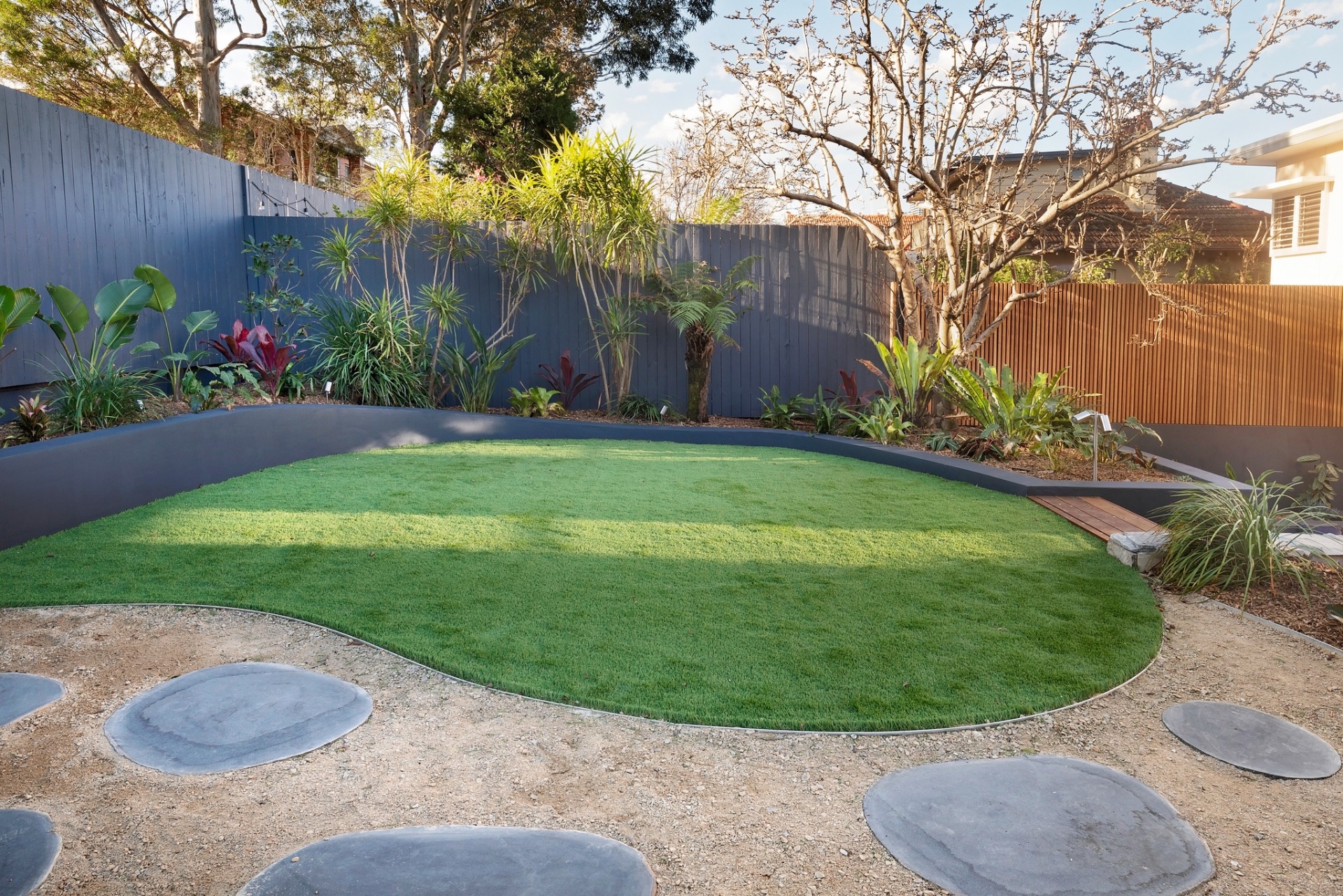Sculpted lawn bordered by rendered planter walls and tropical planting