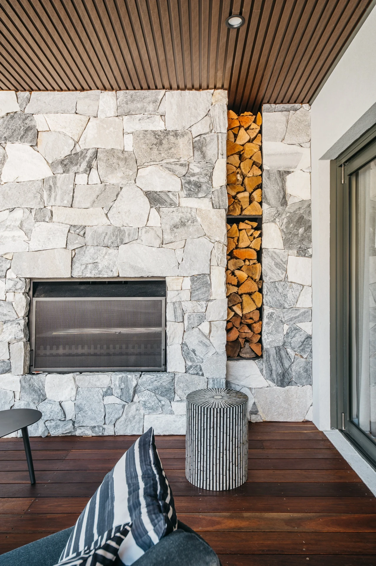 Natural stone cladding with built-in fireplace and open fire-wood storage