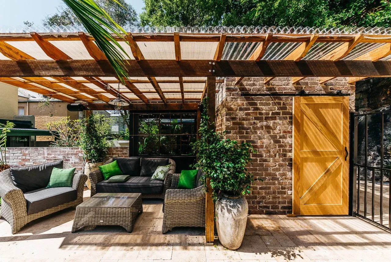 Hardwood pergola with sliding barn door and steel-framed window to the rear of the terrace