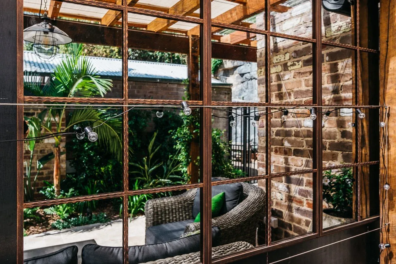Detail of the steel-framed window and festoon lighting reflecting the Glebe courtyard garden