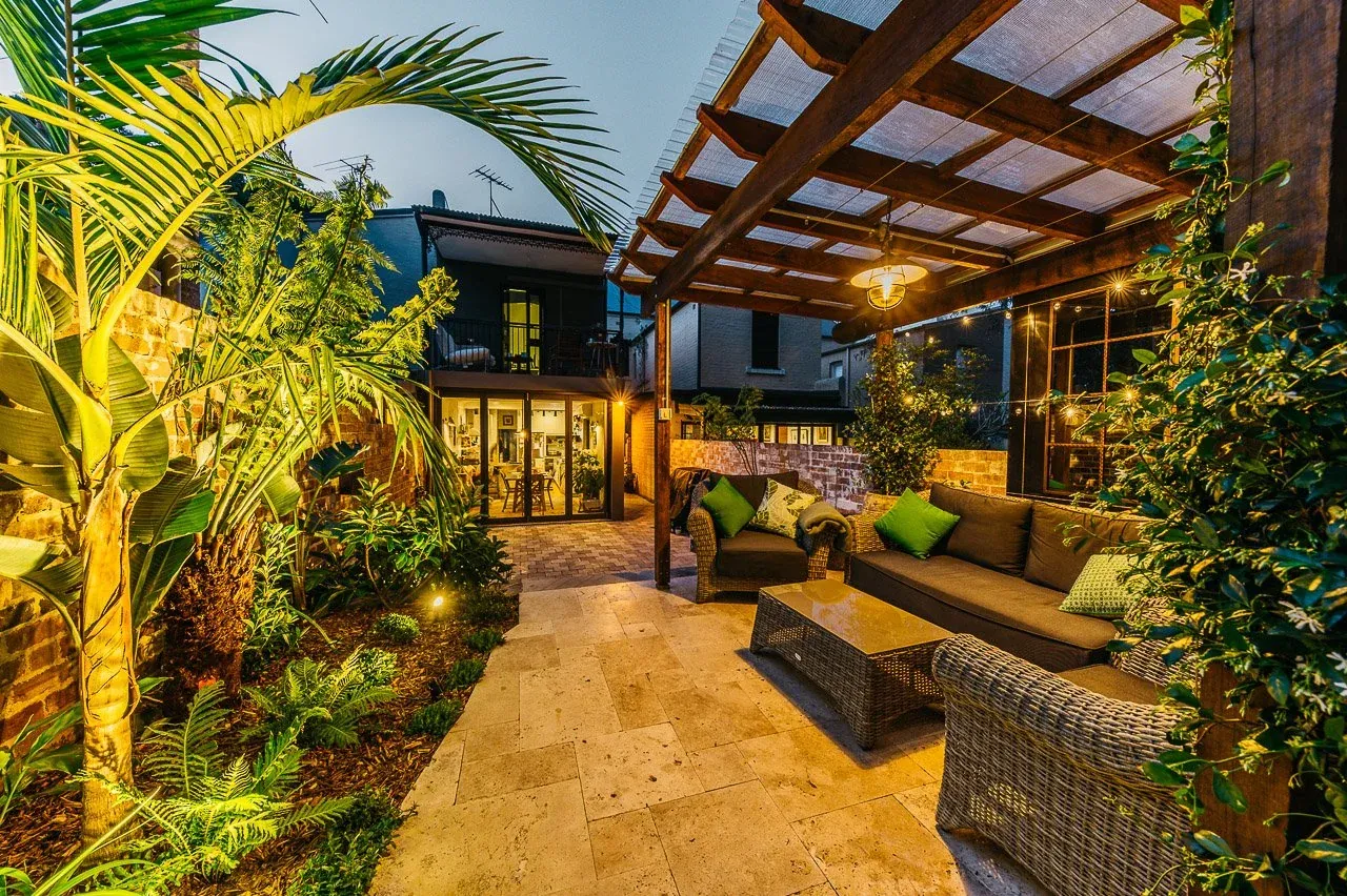 Wide dusk view of the Glebe courtyard looking back to the lit terrace interior