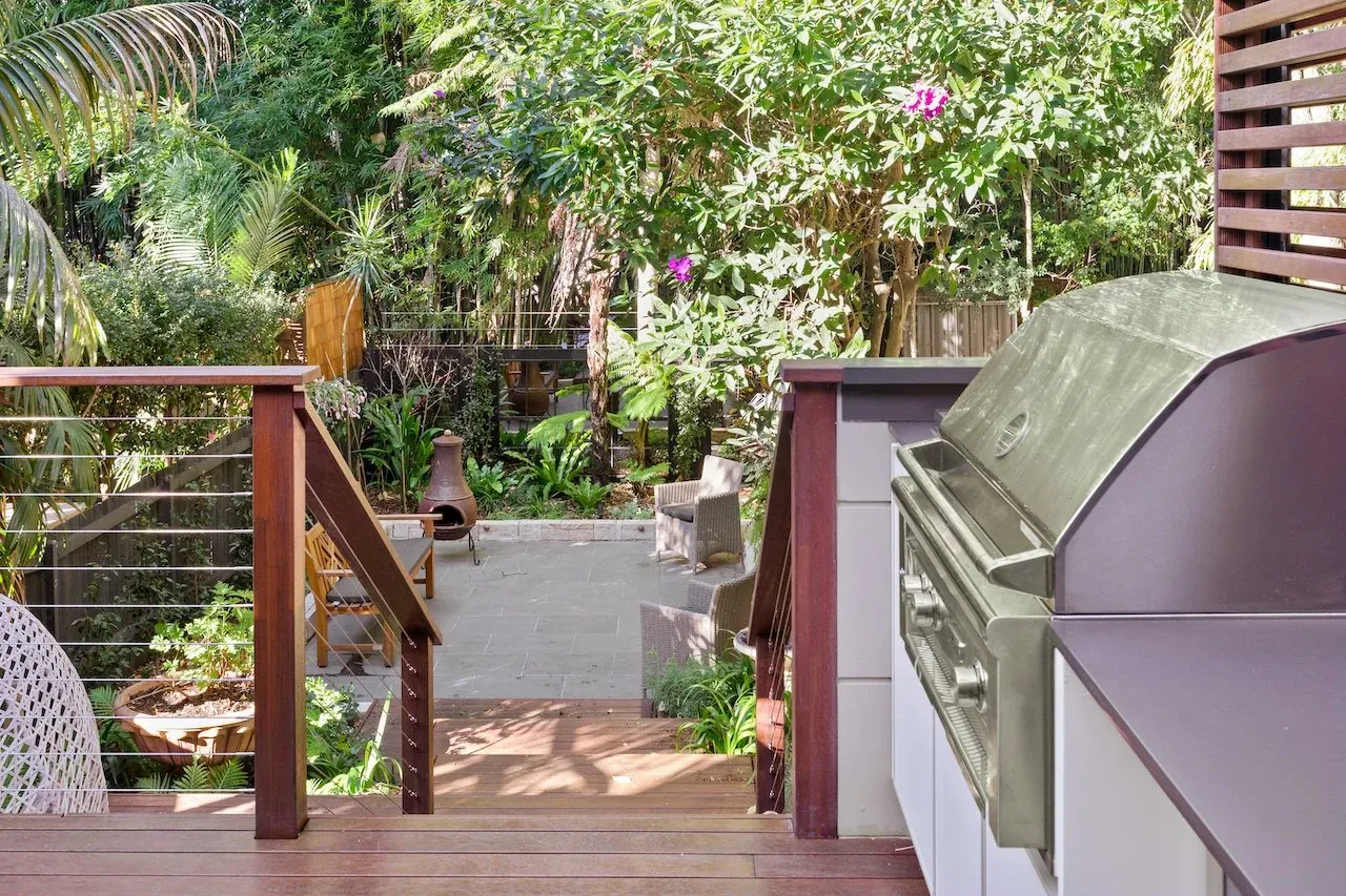 Outdoor kitchen with stainless BBQ and stone benchtop beside the hardwood deck balustrade