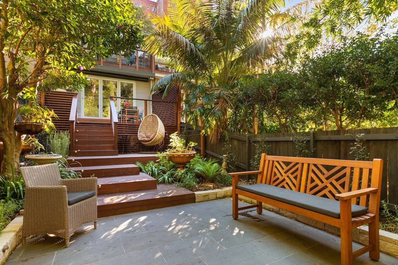 Bluestone paved terrace with timber bench seat and sandstone garden edging in Kirribilli