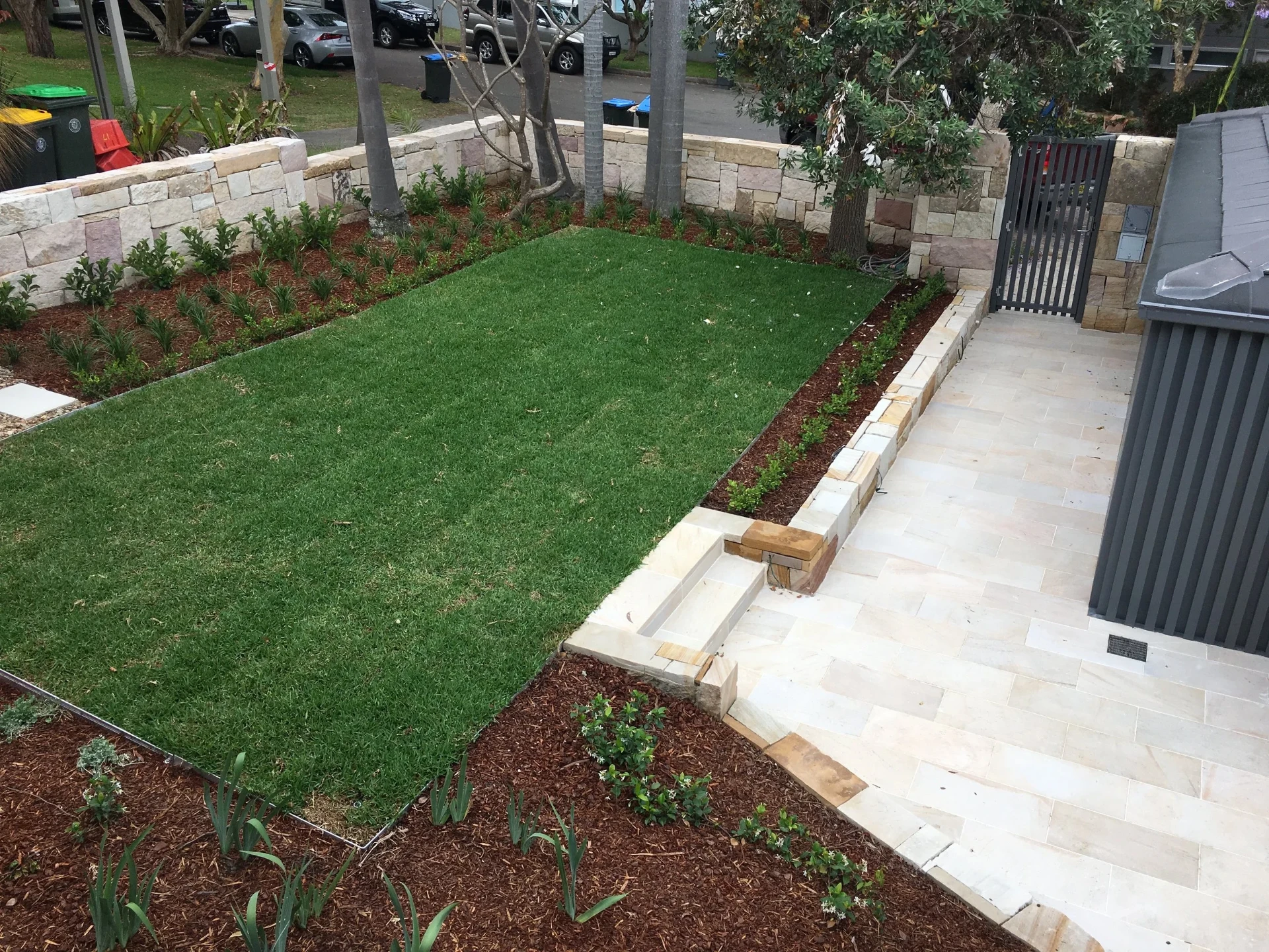 Elevated view of new turf lawn, sandstone edging and stone paving beside the entry gate