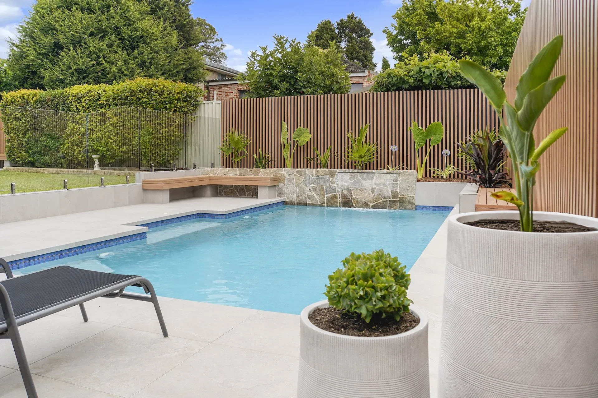 Pool terrace with sun loungers, feature pots and slat-screened boundary