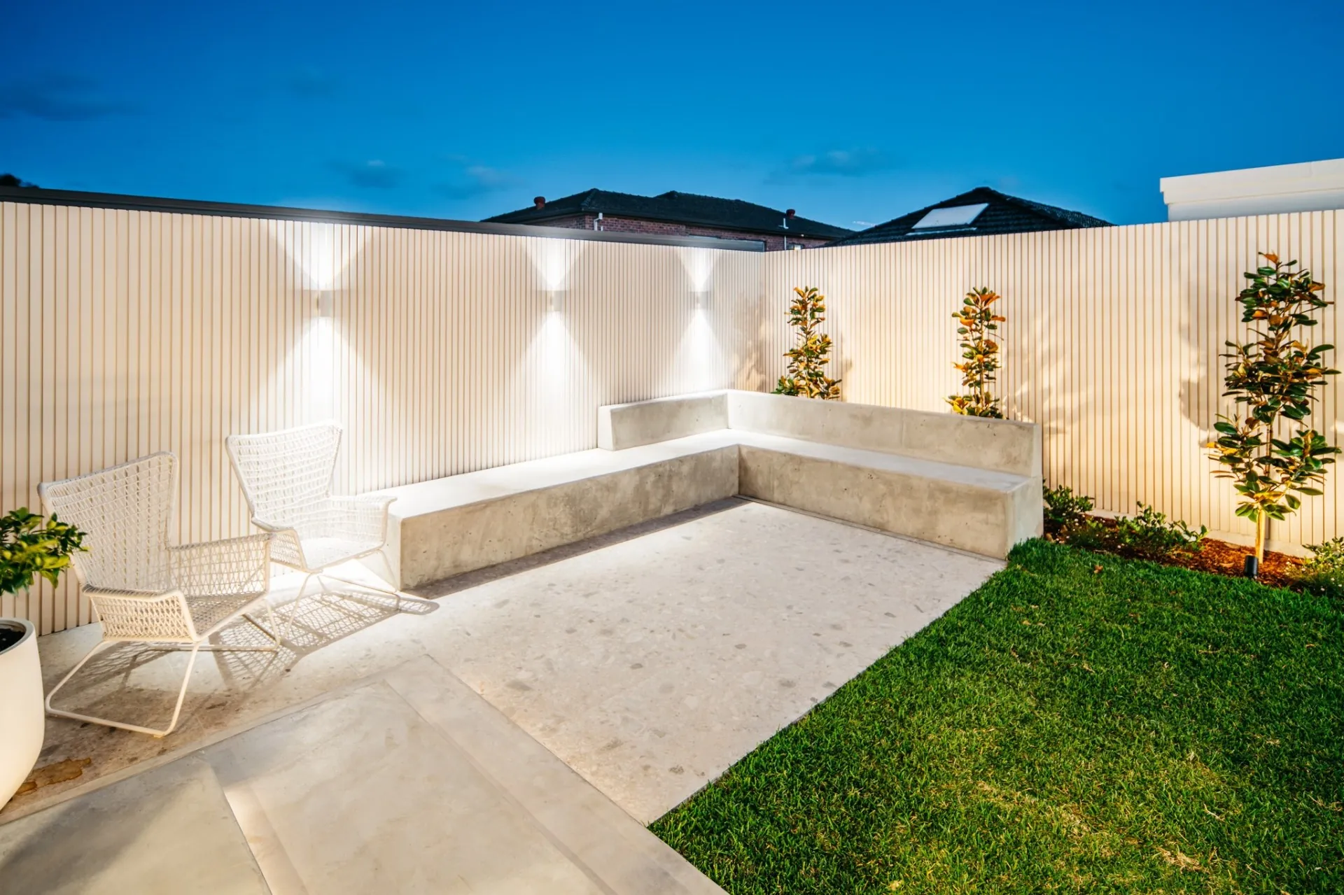 Corner detail - board-formed concrete bench, wicker chairs and uplit fence
