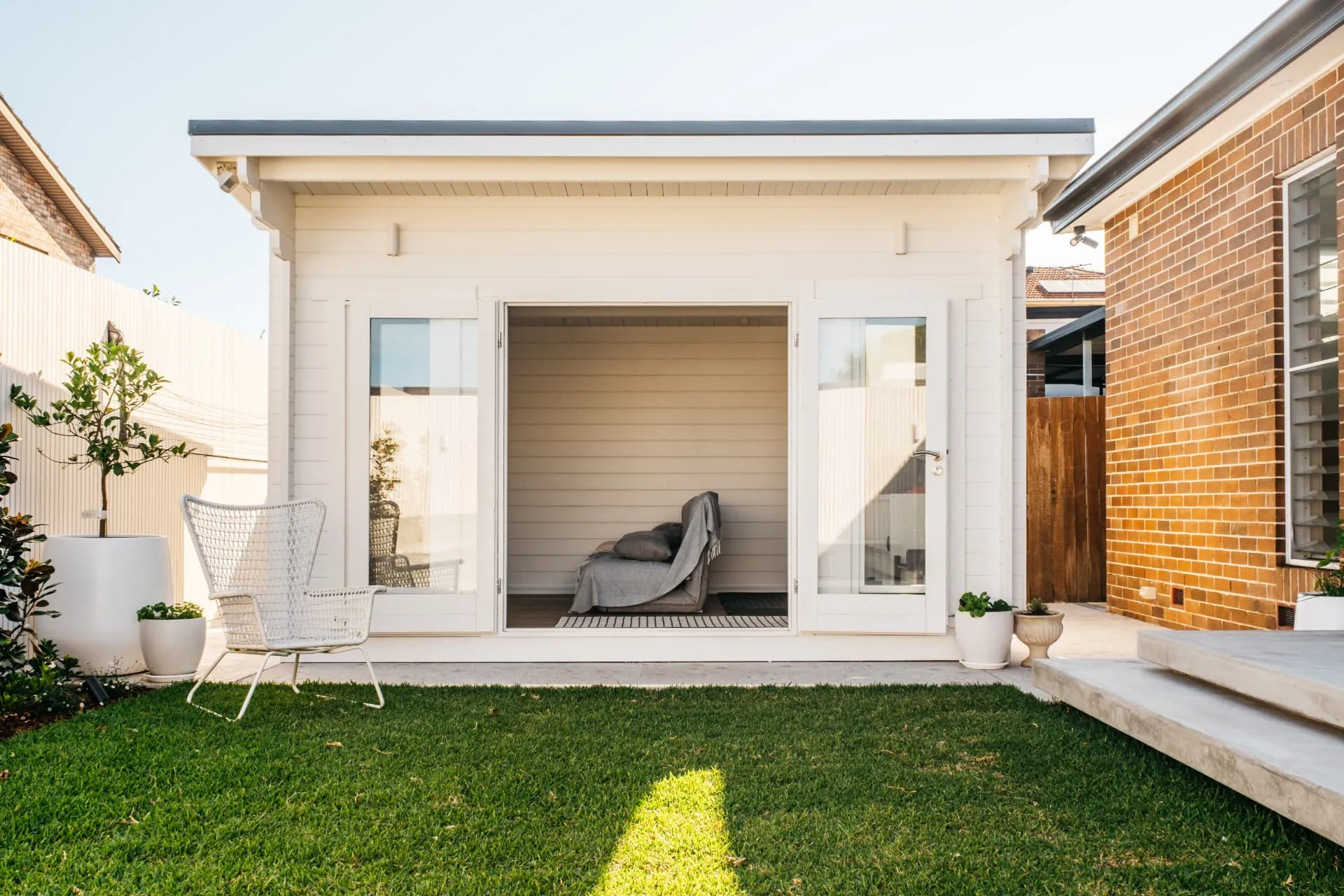 Daytime elevation of the white cabana with bifold doors open to the lawn