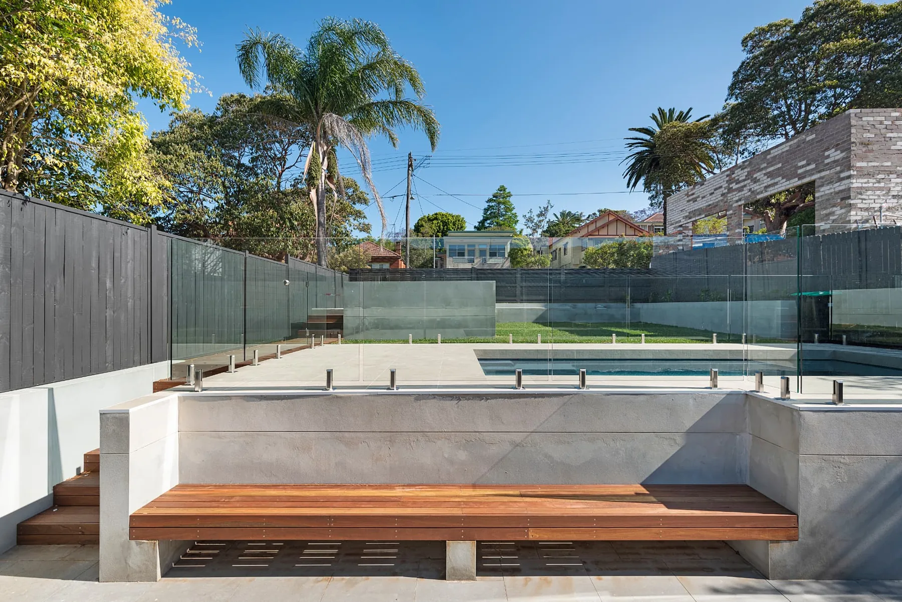 Built-in hardwood bench seat set into a rendered wall facing the pool terrace