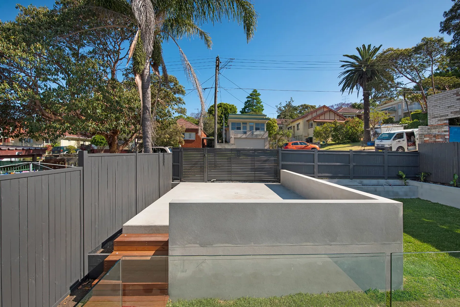 Rendered retaining and concrete parking pad with slatted steel driveway gates at the Seaforth frontage