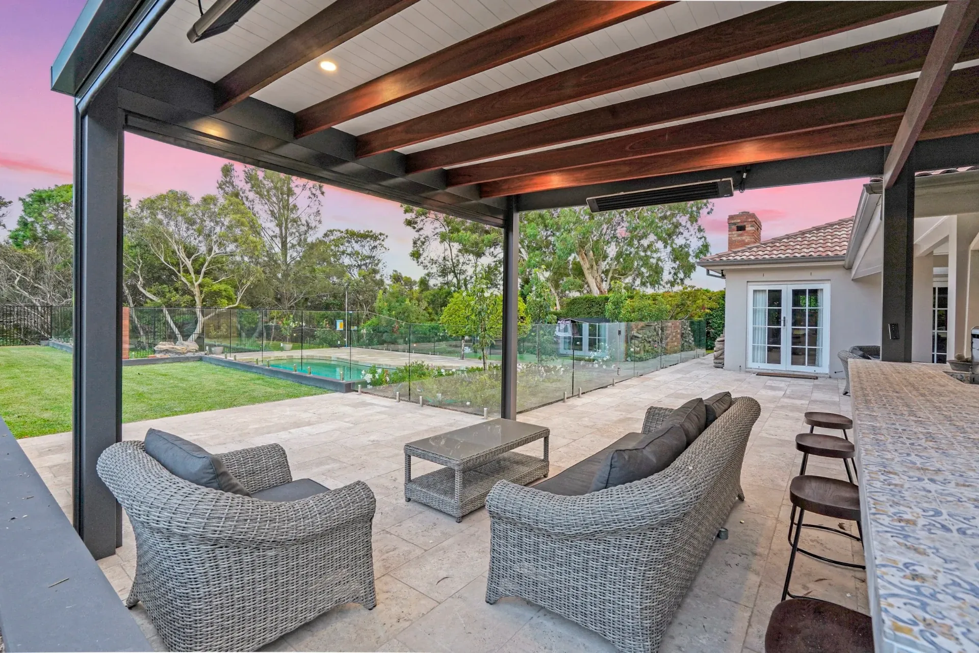 Lounge setting under the covered pergola looking across the lawn to the pool