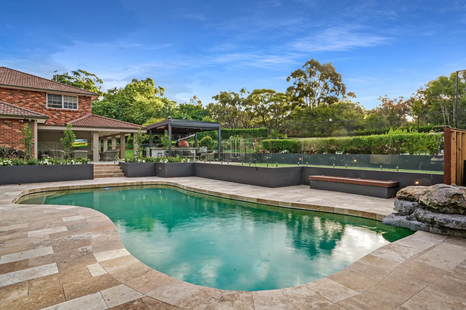 Pool with paved coping and glass fencing set within the landscaped rear yard