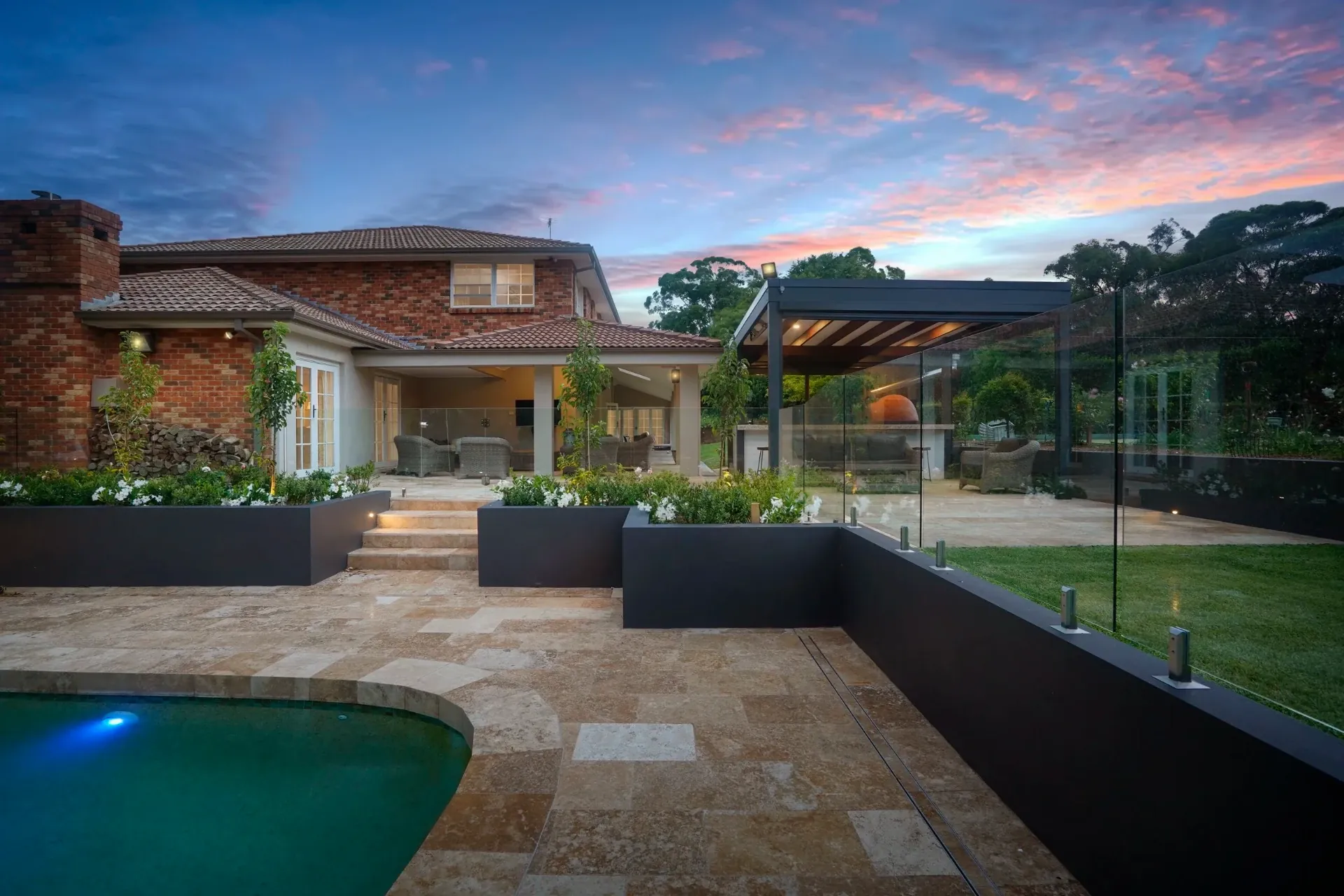 Paved pool terrace and steps up to the covered entertaining areas at dusk